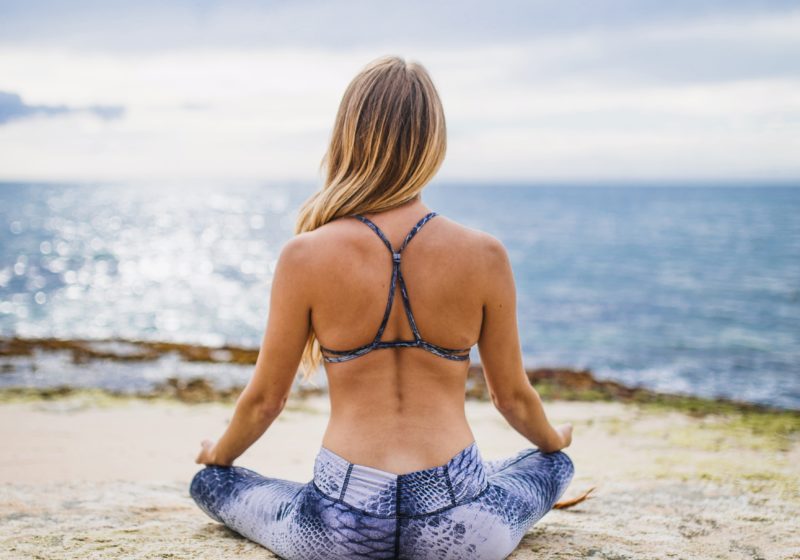 woman in a meditative yoga pose on the beach by the water
