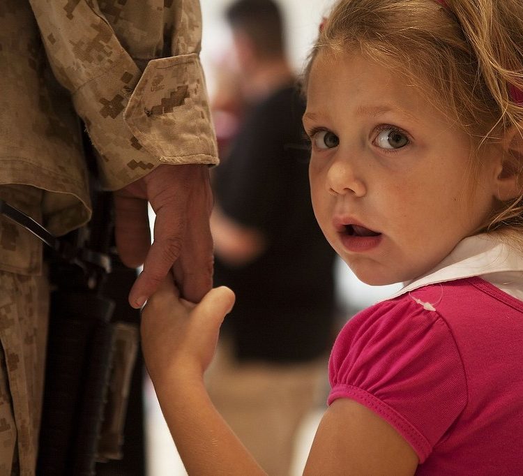 Young girls holds the hand of her military parent